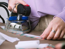 Hands ironing fusible interfacing onto on pink and green fabric.