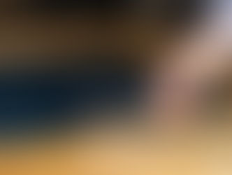 Hand cuts navy fabric with silver sewing scissors on a wooden table.