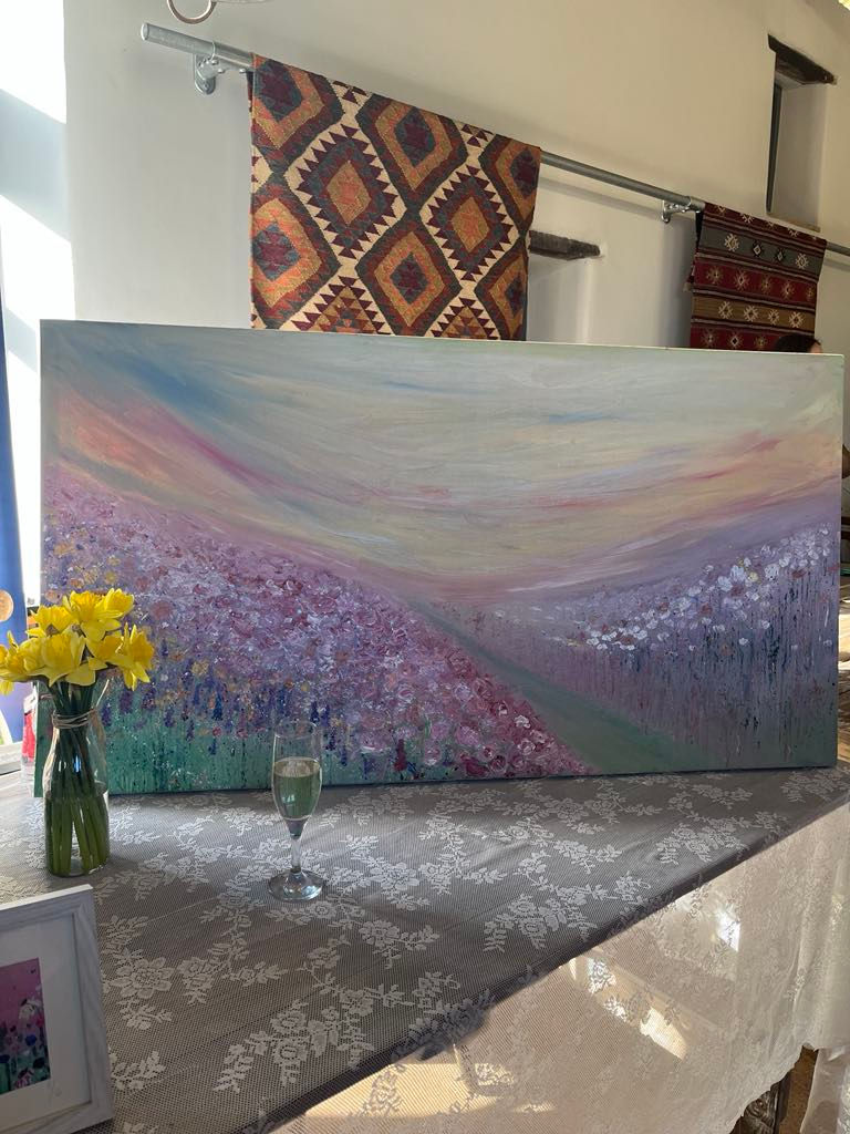 unique wedding day ideas - a painted canvas with daffodils and a champagne glass in front of it on a display table