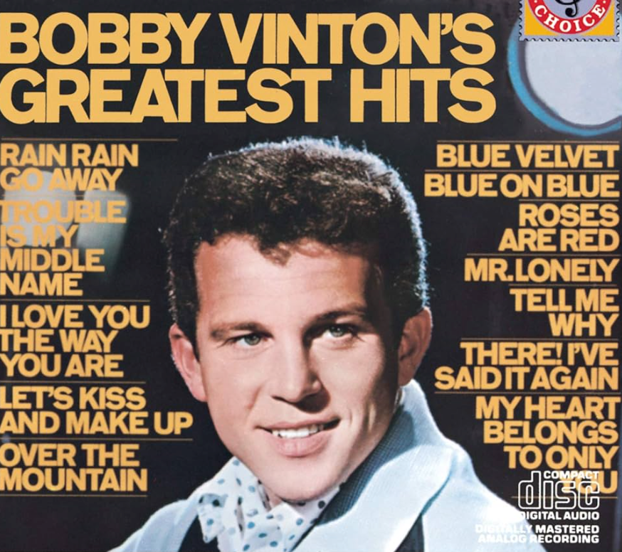 Album cover that says "Bobby Vinton's Greatest Hits: Rain Rain Go Away , Trouble is my middle name, I love the way you are, Lets kiss and make up, OVer the mountain, blue velvet, blue on blue, roses are red, Mr.s Lonely, Tell me why, There! I've said it again, My heart belongs to only you" with. a photo of Bobby Vinton