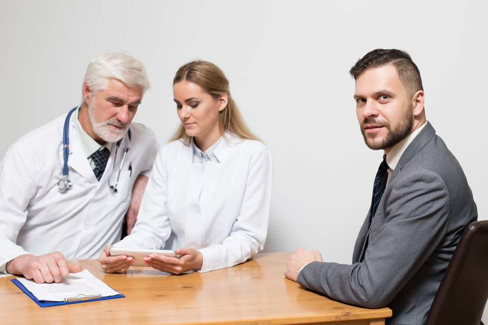Doctor meeting an injured worker with a San Francisco workers’ compensation lawyer present during consultation to support the claim process.