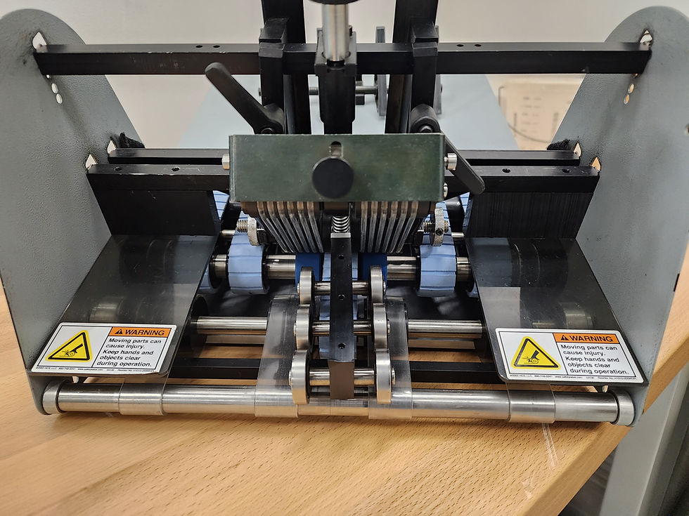 A close-up view of a machine with warning labels indicating moving parts and safety precautions.