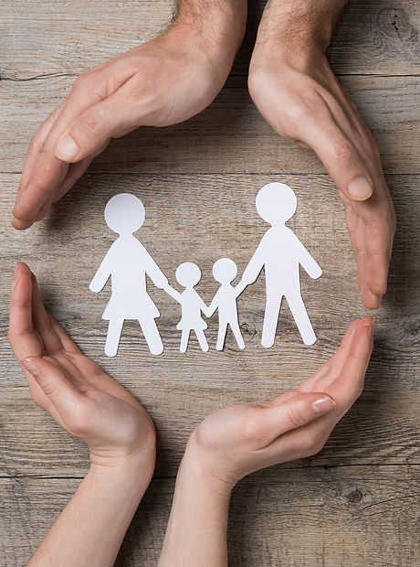 Close up of female and male hands protecting a paper chain family. Top view of two hands form a circ