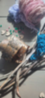 Natural materials collected on a nature walk for our open-ended nature craft for kids. The image features sticks and birch bark as well as yarn and gems from our craft bin.