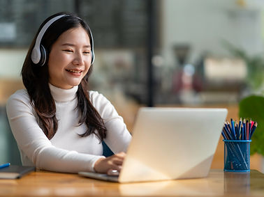 Photo of a college student participating in a workshop on her laptop and smiling.