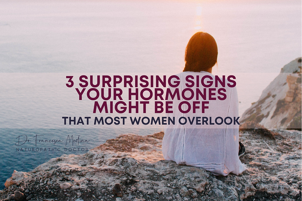 Woman in white sits on rocky cliff at sunset overlooking sea. Text reads: 3 surprising signs your hormones might be off that most women overlook.