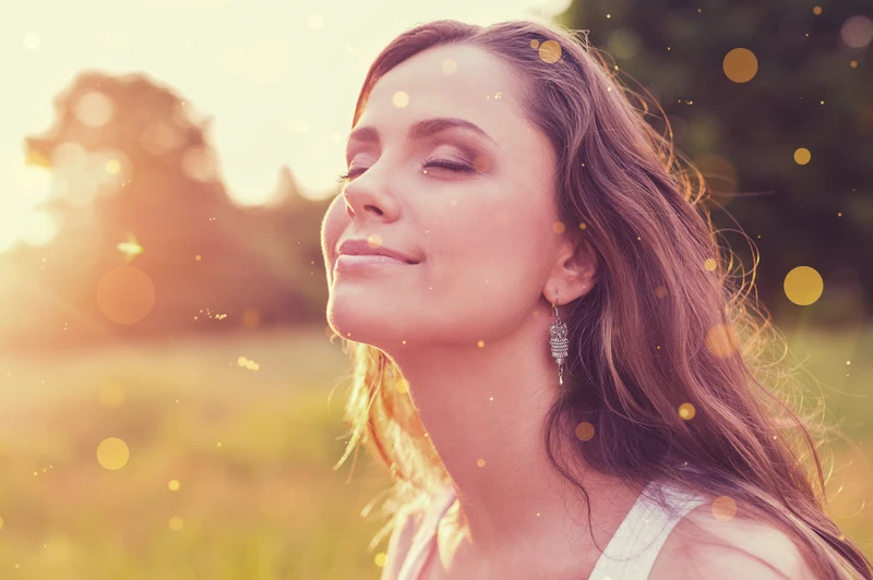 Woman standing in sunlight with eyes closed, embodying clarity, intention, and new beginnings during a New Year manifestation program