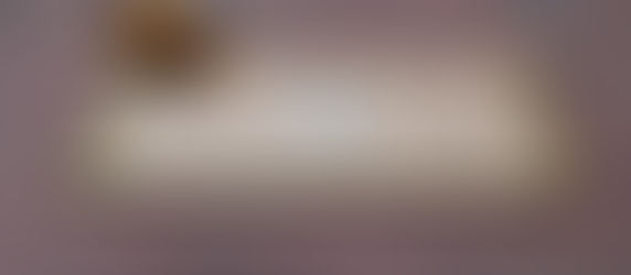 A yellow HoistCam camera in mid-air, about to impact a piece of cardboard on a brick sidewalk.