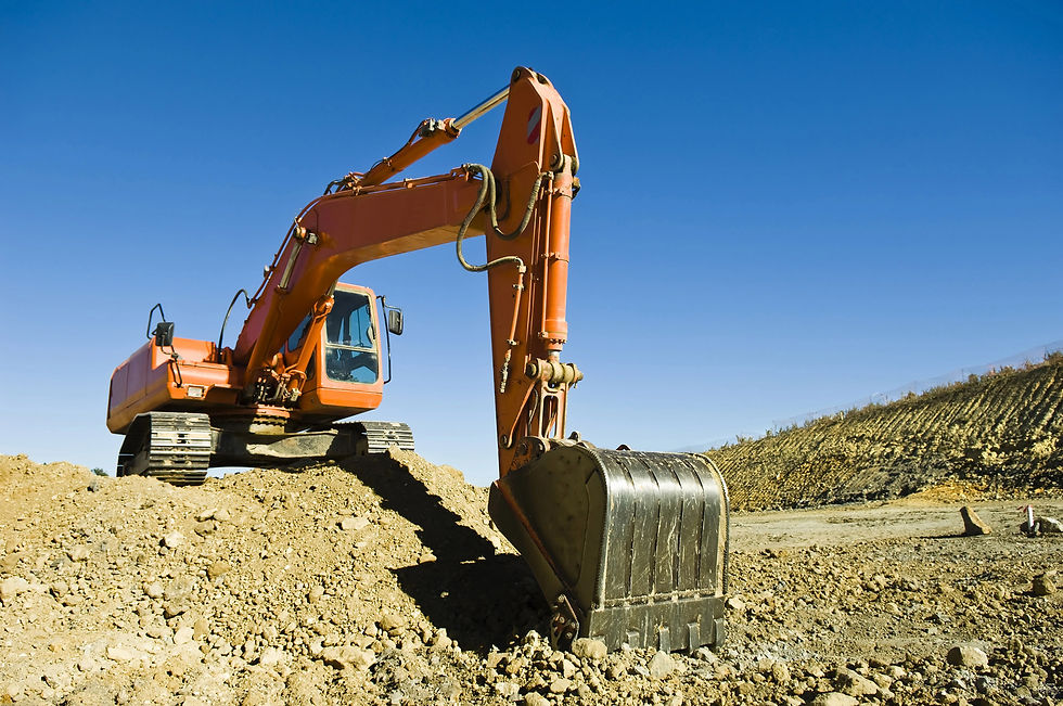 Orange excavator parked on a dirt mound at a construction site under a clear blue sky.