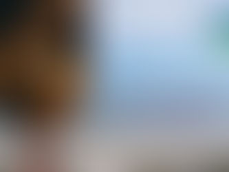  A yellow and black HoistCam camera is mounted on a striped, industrial-looking metal structure, possibly part of a crane or pier. In the background, there's a wide sandy beach with the ocean stretching out to the horizon under a partly cloudy sky. Several people are visible walking on the beach in the distance. Overlaid on the image are the words "Enhanced Operator Visibility" in red and blue text. The "HoistCam" logo is in the top right corner.