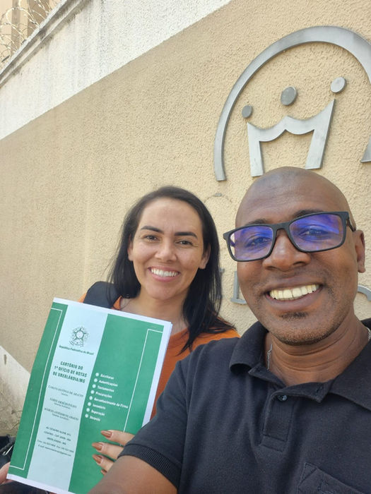 Dois sorrindo segurando um documento e Dias & Santo, com emblema ao fundo.