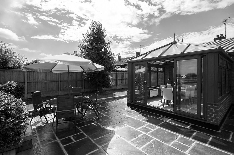 A general exterior view of a wood effect UPVC conservatory on a sunny day being used as a