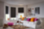 Black pleated blinds in modern, colourful living room with large white sofa