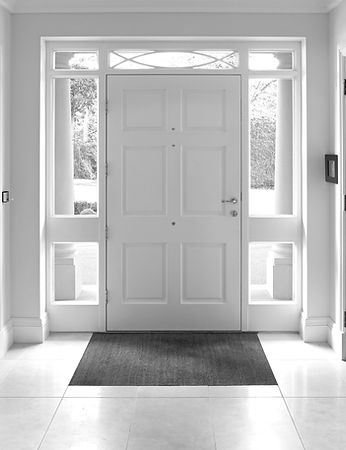 a front door entrance to a grand house. The wood panelled front door and frame are painted