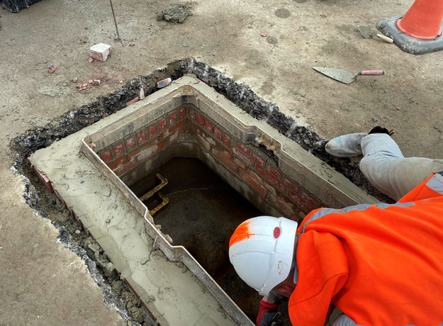 Worker looking down a drain