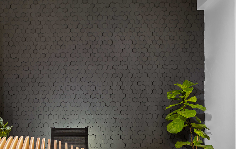 Dark hexagon-patterned GFRG wall panels creating a bold textured feature in a contemporary interior space.
