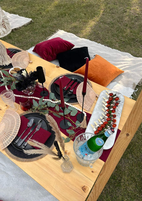 Close-up of the Falling Ember picnic setup with black and burgundy decor by Sunkissed Design & Co.