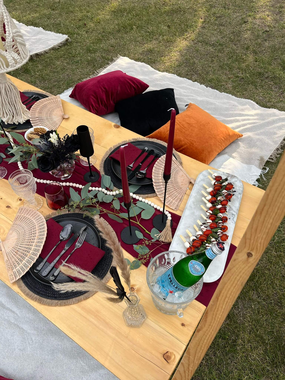 Close-up of the Falling Ember picnic setup with black and burgundy decor by Sunkissed Design & Co.