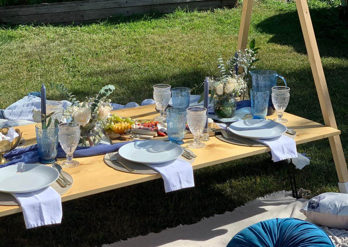Picnic table setup with blue and white accents in front of a barn and classic old car by Sunkissed Design & Co.