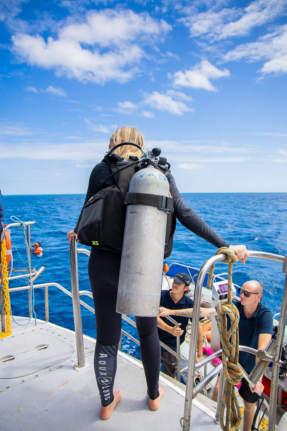 Female scuba diver preparing to enter the ocean with full dive gear during a Whitsundays Great Barrier Reef diving adventure.