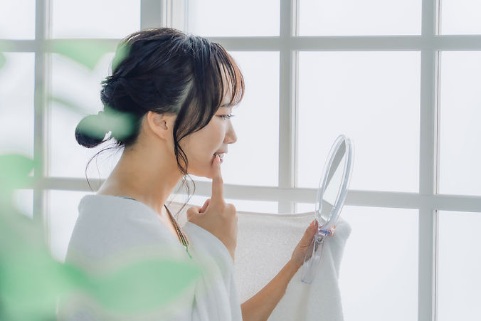 鏡を見て歯を気にしている女性