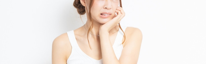 顎が痛くて手で押さえる女性
