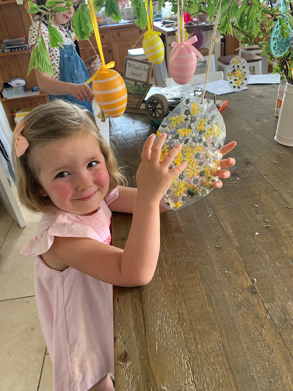 Create pretty Easter-themed flower decorations to decorate your house with. Here Claudine's daughter makes a laminated hanging egg-shaped decoration using daisies and buttercups collected by the kids from the garden