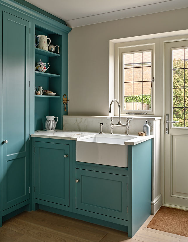 Bespoke teal kitchen cabinetry with Belfast sink, marble worktop and open shelving in a luxury interior