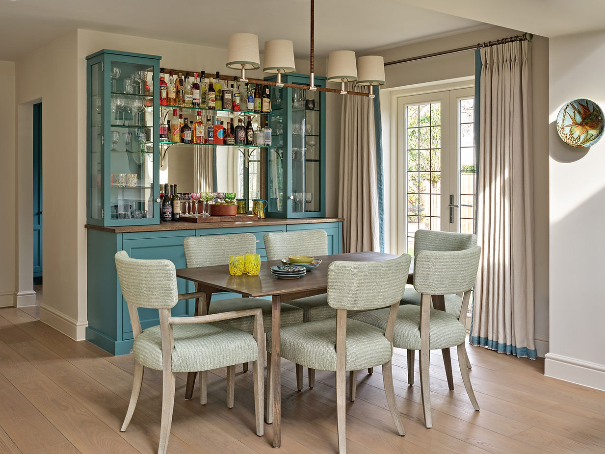 Dining area with bespoke bar cabinetry, upholstered chairs and pendant lighting in a luxury interior