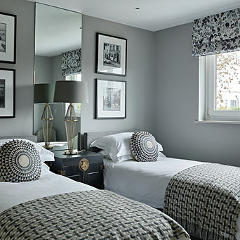 Twin bedroom with upholstered beds, mirrored wall and monochrome styling, elegant guest room