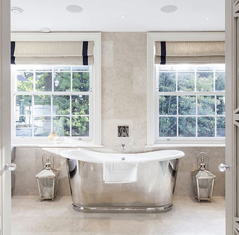 Bathroom with freestanding metal bathtub, twin windows and stone finishes, luxury spa-style interior