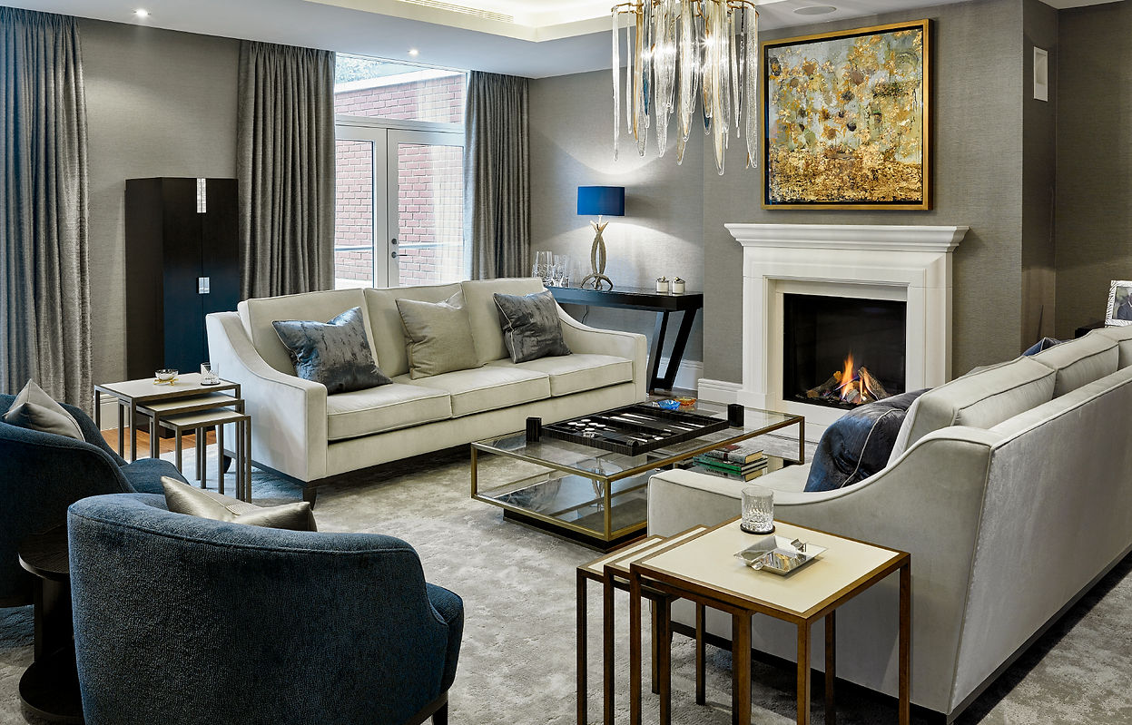 Modern London townhouse living room with neutral sofas, glass coffee table, fireplace and statement chandelier