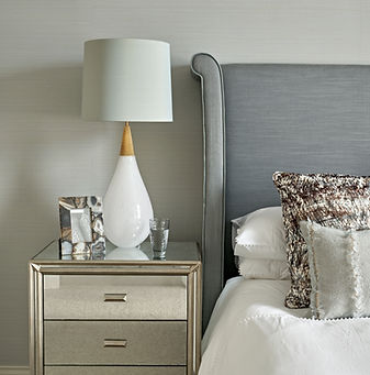 Bedroom detail with bedside table, lamp and upholstered headboard, soft neutral palette