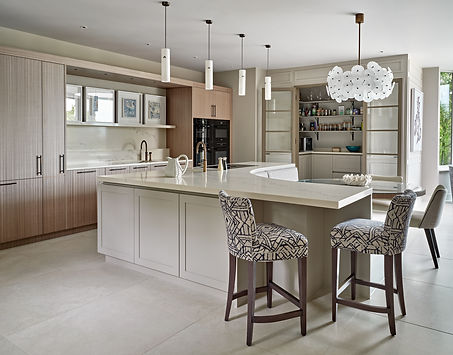 Kitchen island with upholstered bar stools and bespoke cabinetry in a luxury open-plan space