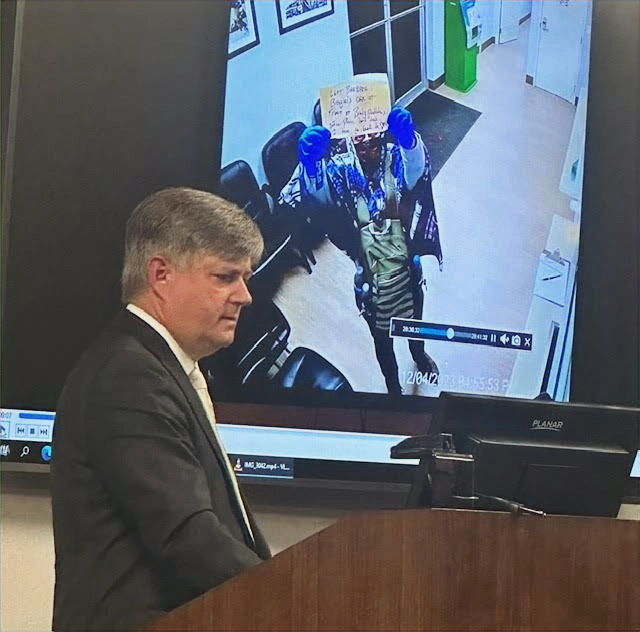 District Attorney Alan Nash showed jurors footage from security cameras at the Stephenville Police Department capturing a masked Broyles holding up a sign for police.