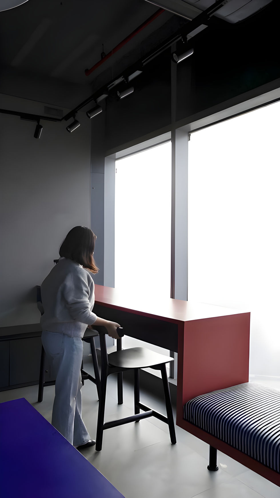 Person arranging chair near window in minimalist room.