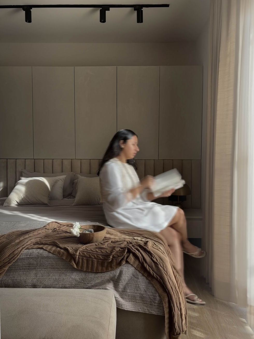 Person reading on bed by window.