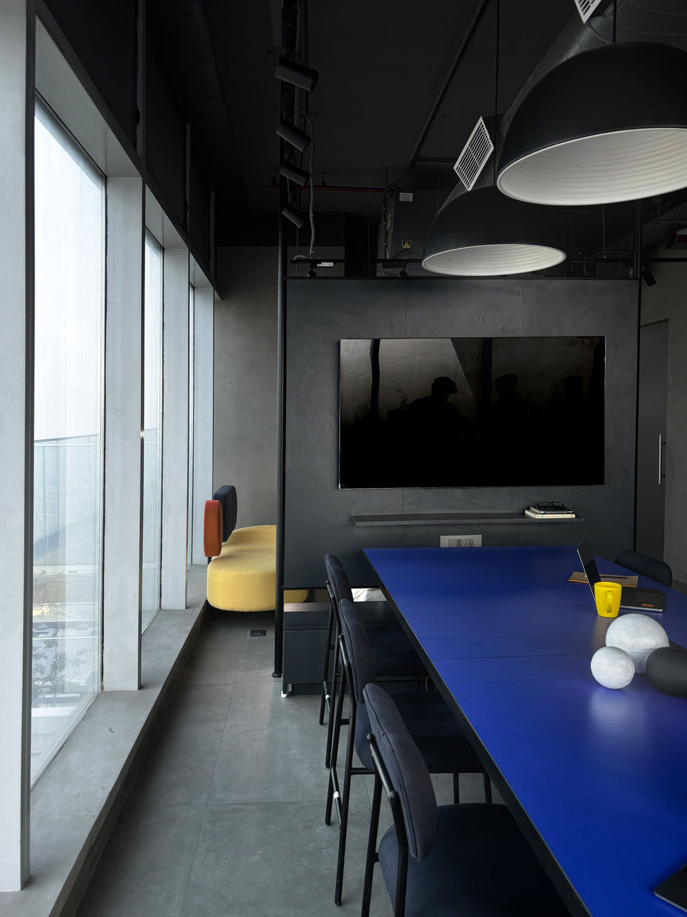 Modern conference room with blue table and large screen.