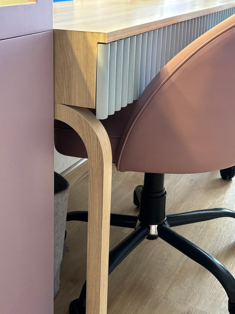 Pink chair and wooden desk with wheels.