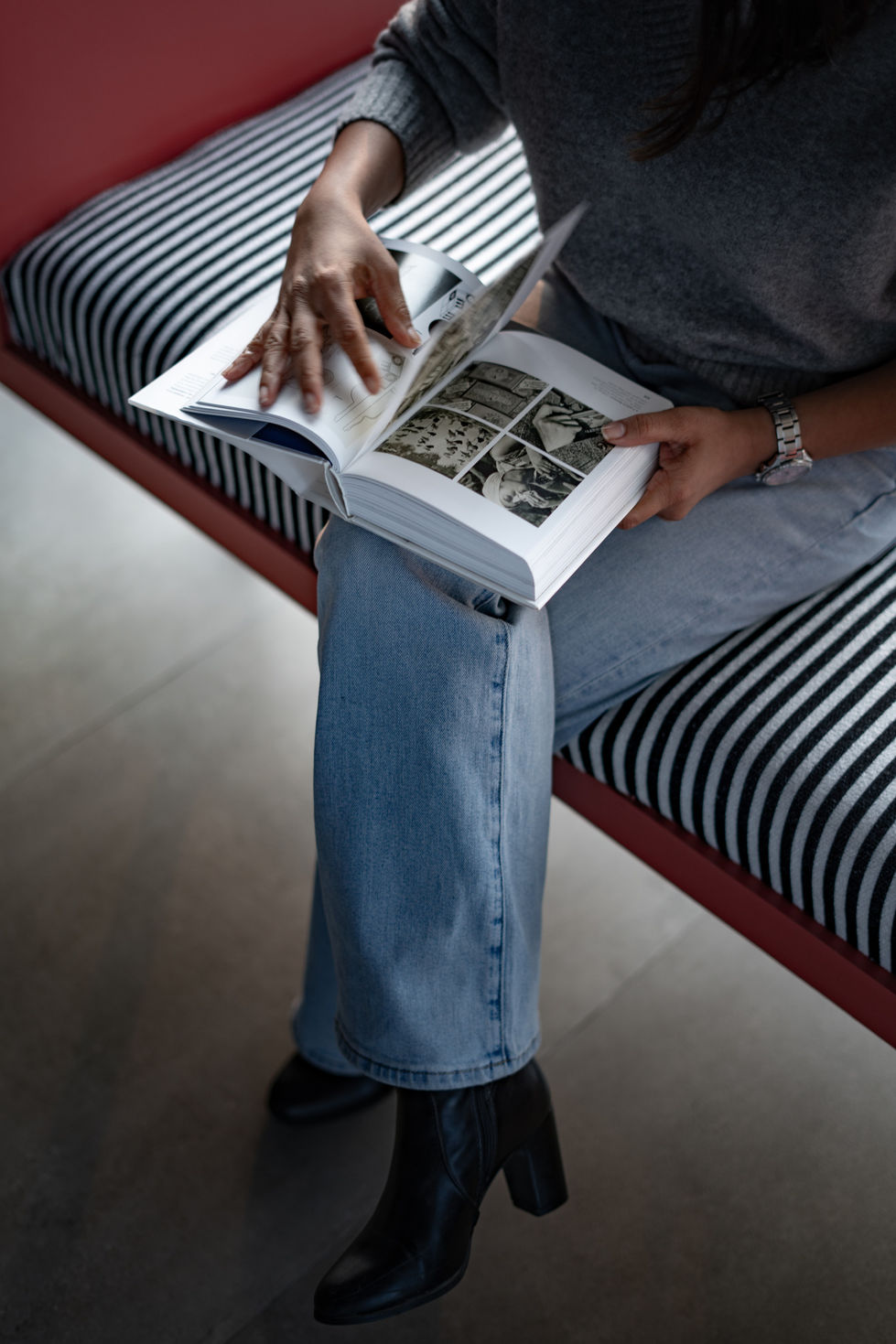 Person reading a book on striped bench in modern office