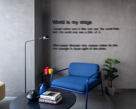 Modern office lounge with blue chair and motivational wall quote.