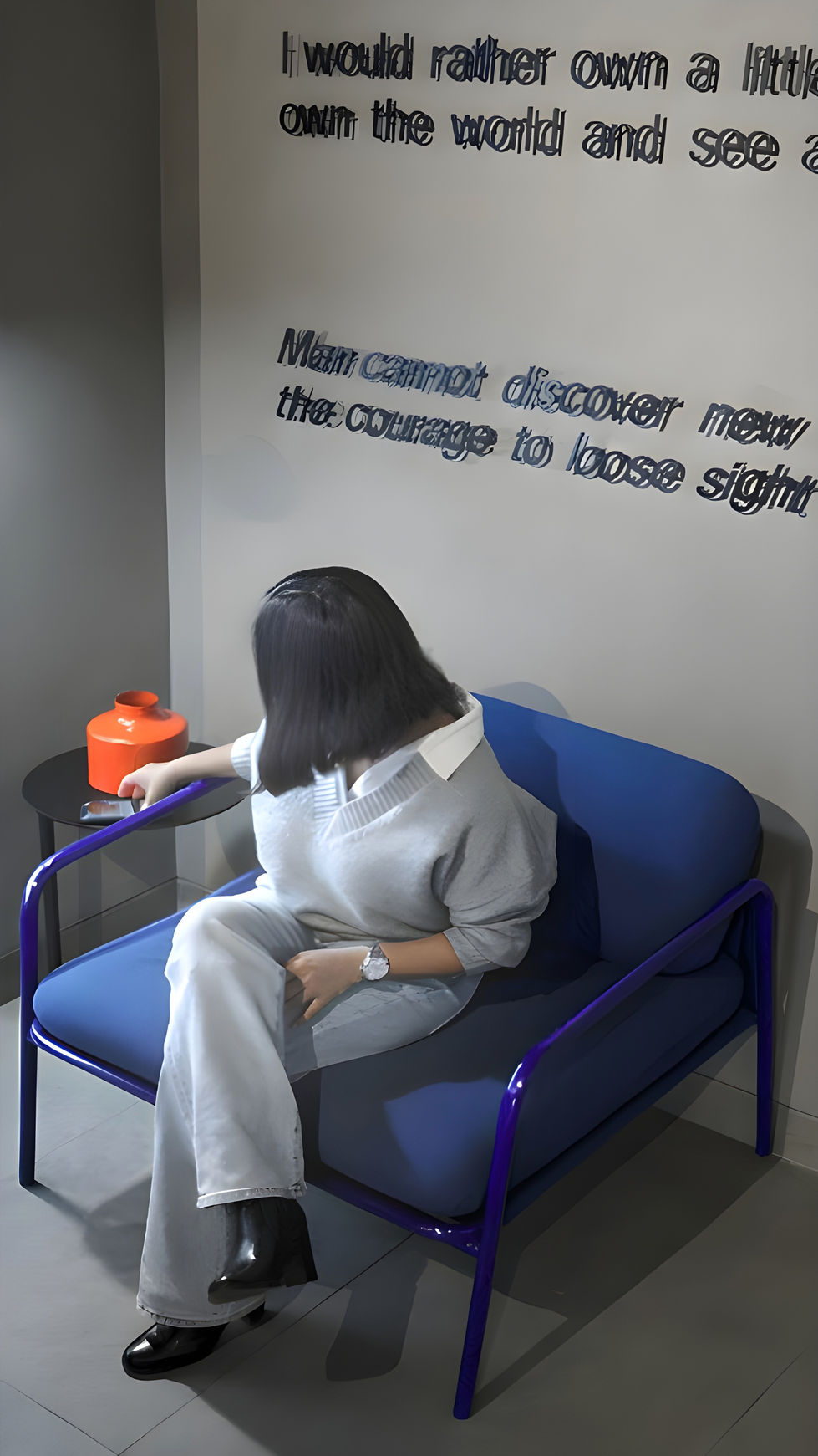 Person sitting on blue couch near motivational quote.