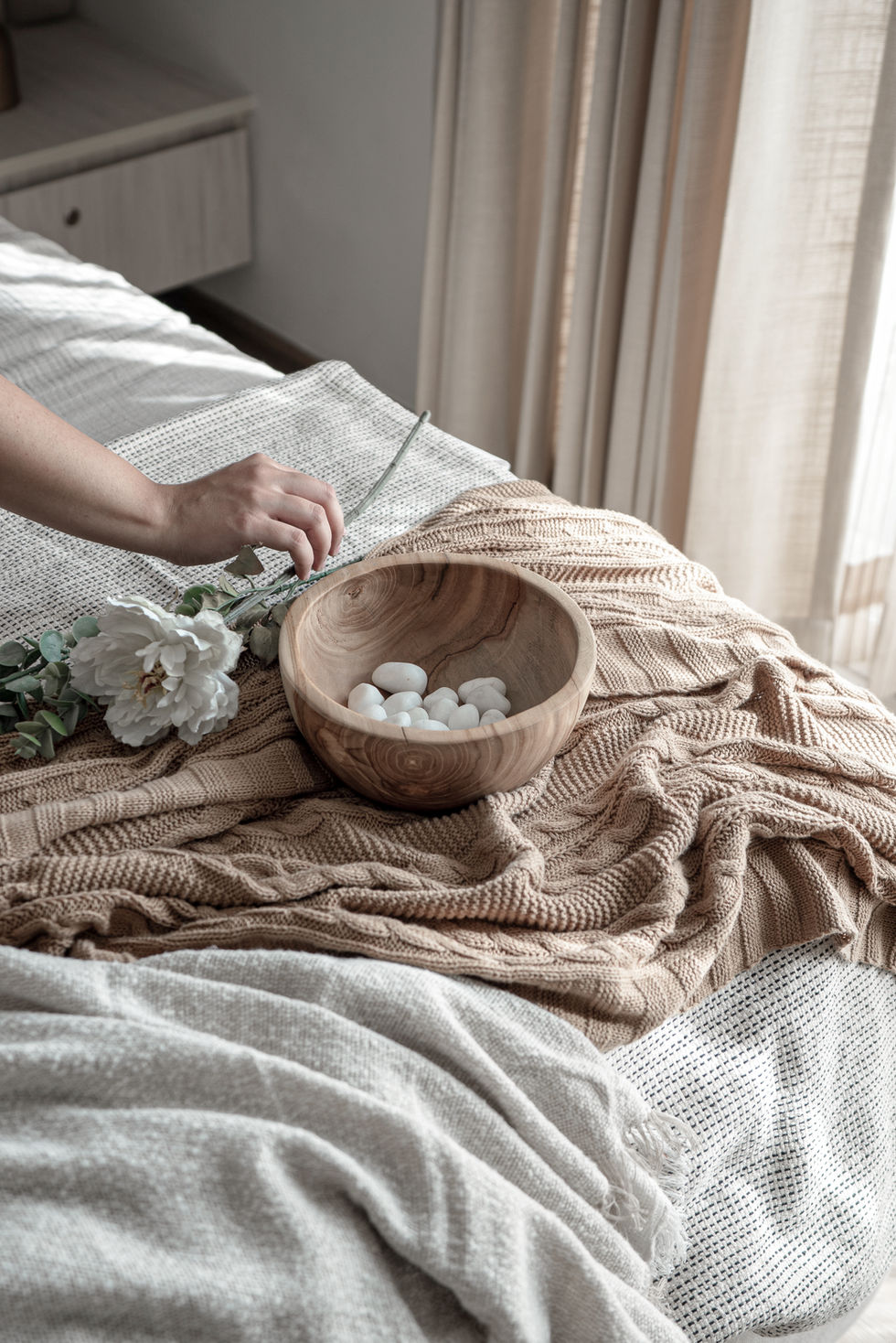 Wooden bowl with stones on a cozy, textured blanket.
