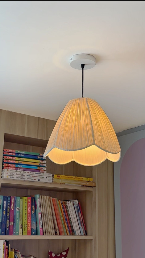 Pendant lamp with scalloped shade, books on shelf.