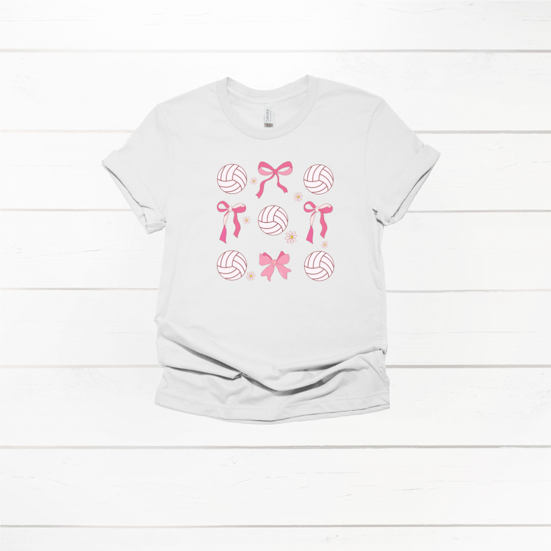 A white T-shirt featuring a design with pink volleyballs and bows arranged in a grid pattern.