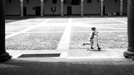 Bambino su monopattino che sfreccia in un cortile del castello sforzesco a milano