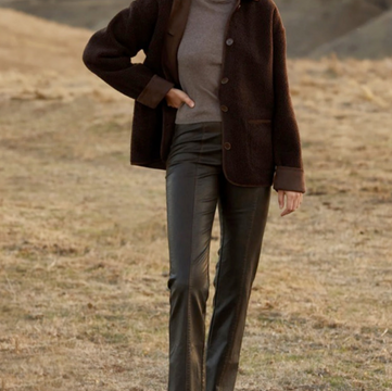 A woman wearing the Zuri Faux Leather Pant in a natural outdoor setting, styled with a turtleneck and jacket for Reed Homestead’s in-store collection.