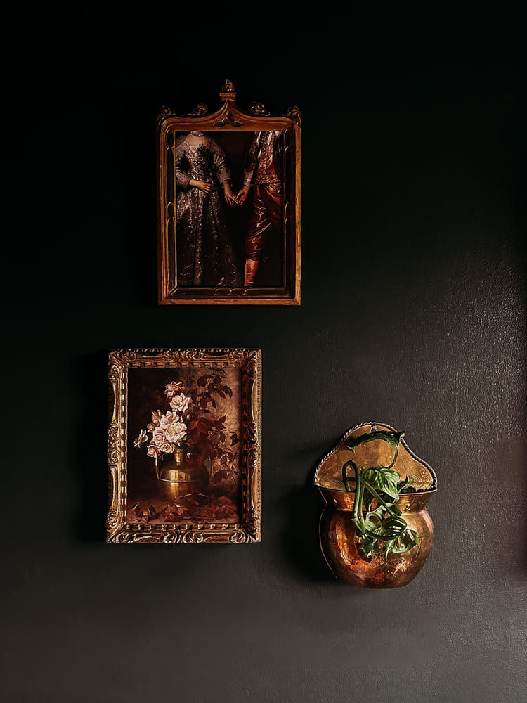 Framed artwork and a wall planter against a dark wall.