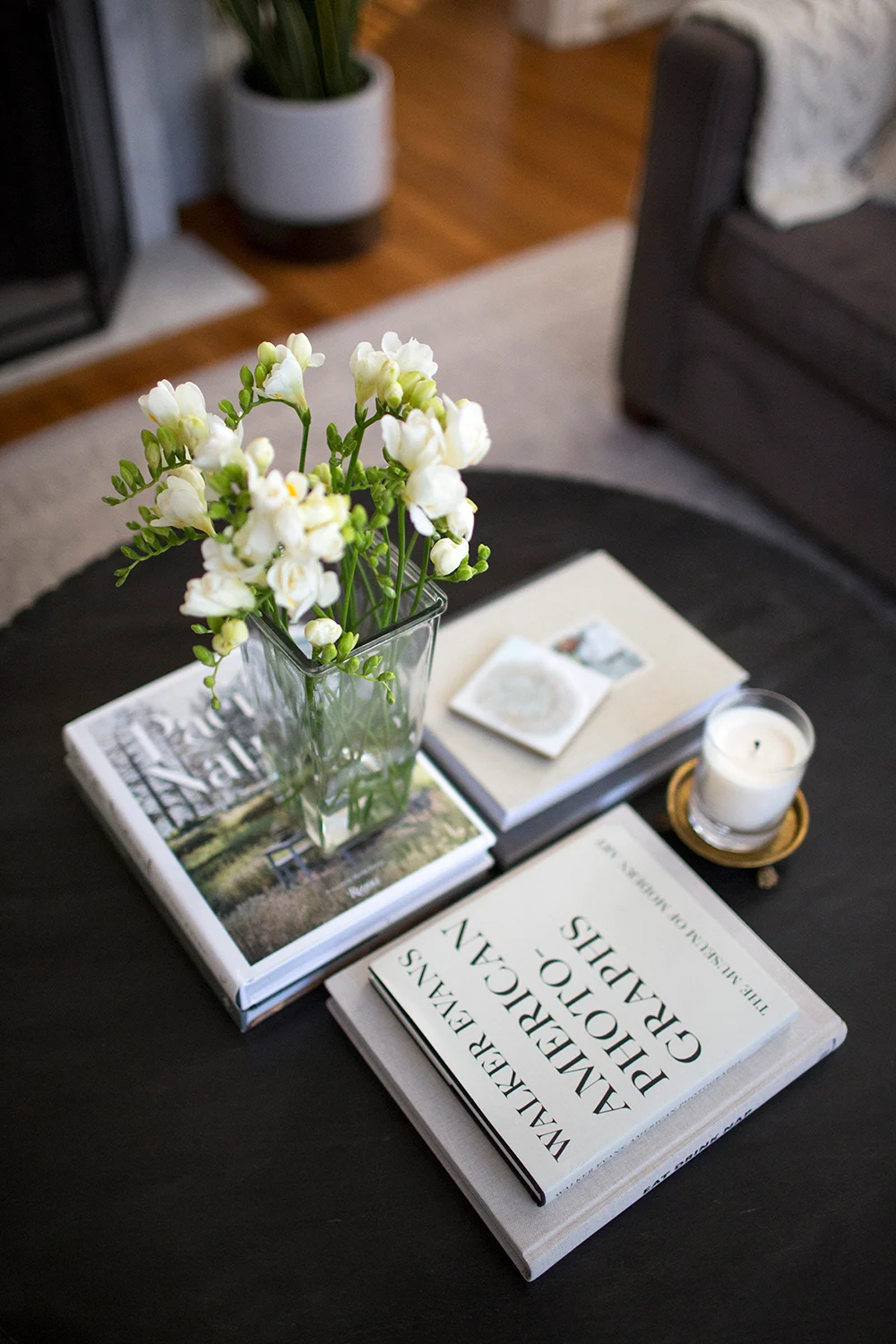 A coffee table with books and white flowers.