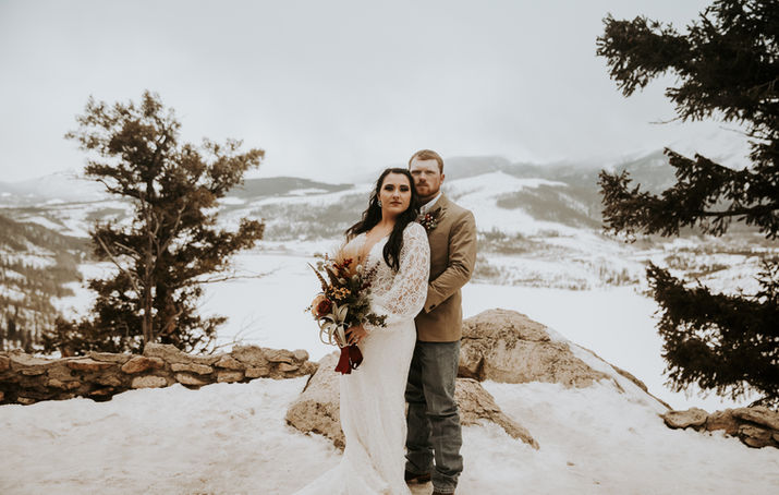 A wedding couple posing in front of mountain landscape.
